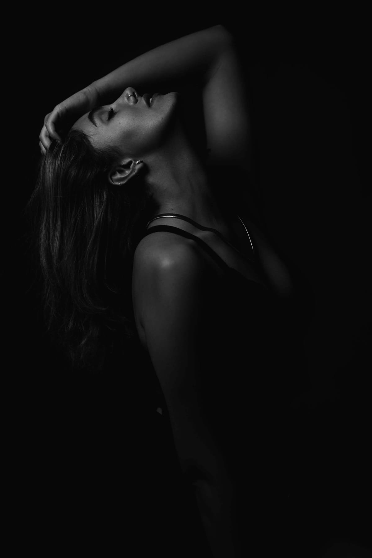 Black and white portrait of a woman in silhouette arching her neck with closed eyes, sensual fine-art photography